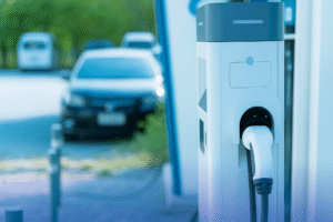 Electric vehicle charging station with a car parked in the background at a commercial site on a bright day